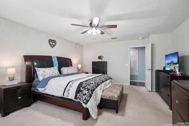 bedroom featuring baseboards, visible vents, a ceiling fan, light colored carpet, and a textured ceiling