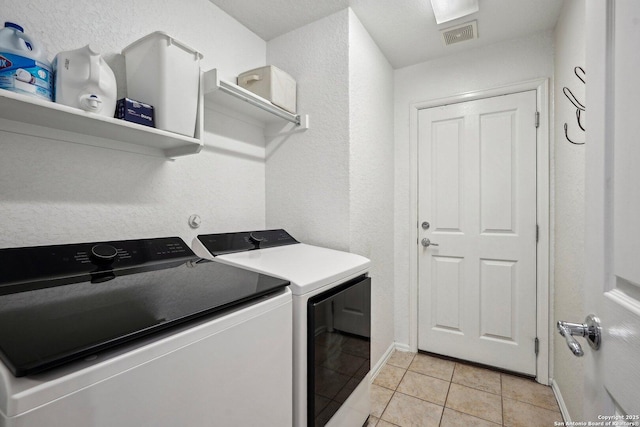 laundry area featuring laundry area, light tile patterned floors, baseboards, visible vents, and separate washer and dryer