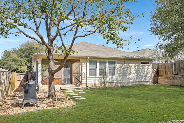 rear view of property featuring a fenced backyard and a lawn