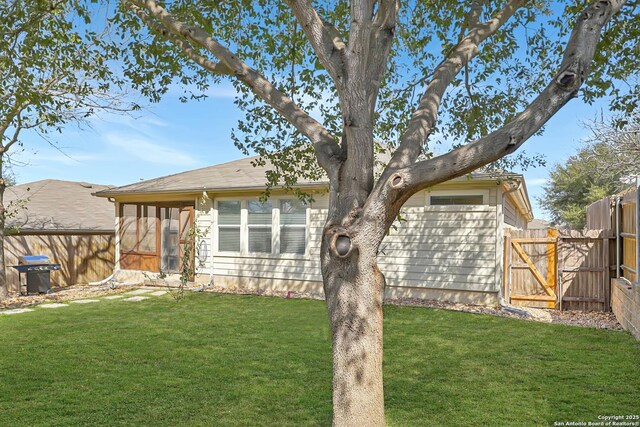 rear view of house featuring a sunroom, a gate, a lawn, and fence