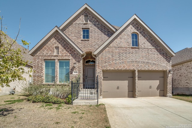 french country style house featuring concrete driveway and brick siding