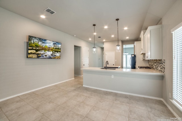 kitchen featuring light countertops, visible vents, freestanding refrigerator, and a sink