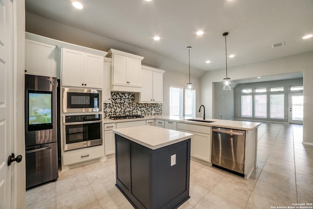 kitchen featuring visible vents, a sink, backsplash, stainless steel appliances, and a peninsula