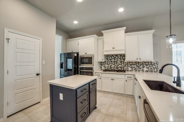 kitchen with tasteful backsplash, decorative light fixtures, appliances with stainless steel finishes, white cabinetry, and a sink