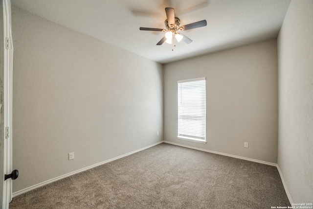 carpeted spare room featuring a ceiling fan and baseboards