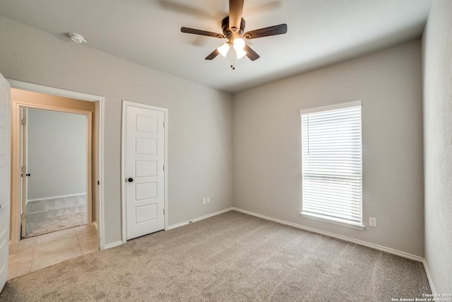 carpeted spare room with baseboards, ceiling fan, and tile patterned flooring