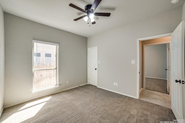 unfurnished bedroom with tile patterned floors, carpet flooring, baseboards, and ceiling fan