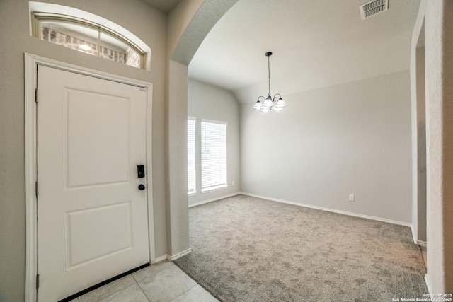 carpeted entrance foyer featuring tile patterned floors, visible vents, arched walkways, baseboards, and a chandelier