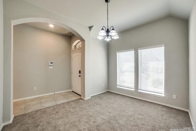 carpeted empty room featuring baseboards, arched walkways, tile patterned flooring, vaulted ceiling, and a chandelier