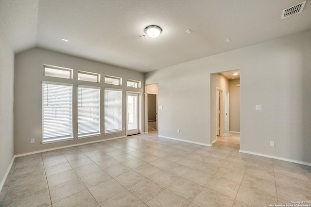 spare room featuring light tile patterned floors, visible vents, baseboards, and vaulted ceiling