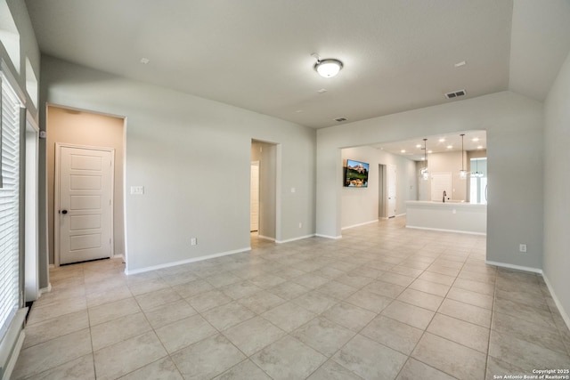 unfurnished room featuring light tile patterned floors, baseboards, visible vents, lofted ceiling, and a wealth of natural light