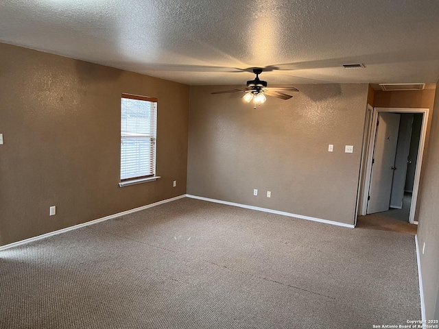 unfurnished room with carpet floors, visible vents, a textured wall, and a textured ceiling