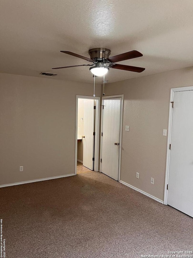 empty room featuring a textured ceiling, ceiling fan, carpet, and visible vents