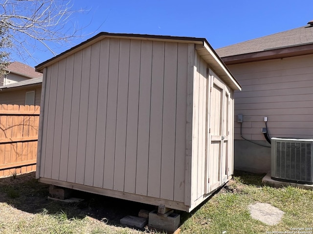 view of shed with cooling unit and fence