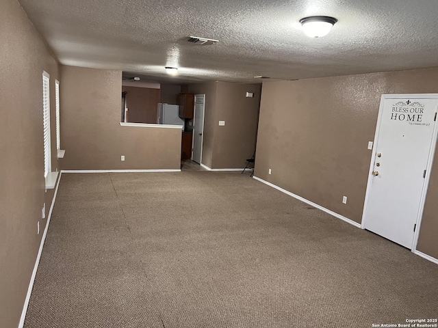 unfurnished room with baseboards, visible vents, a textured wall, a textured ceiling, and carpet flooring