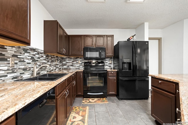 kitchen with light tile patterned floors, dark brown cabinetry, a sink, backsplash, and black appliances