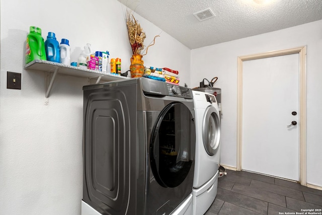 clothes washing area featuring laundry area, visible vents, independent washer and dryer, and a textured ceiling