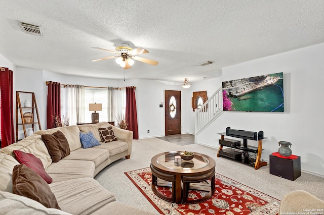 living area with carpet, stairs, visible vents, and ceiling fan