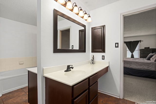 full bath with ensuite bathroom, a textured ceiling, vanity, and a bath