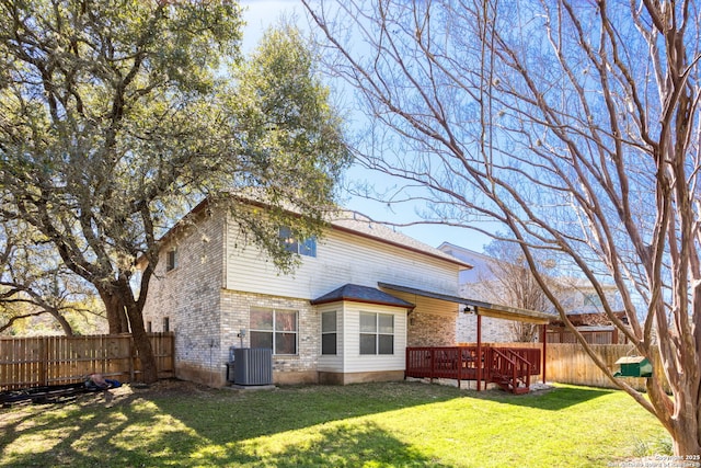 rear view of house featuring brick siding, a yard, central AC, a deck, and a fenced backyard