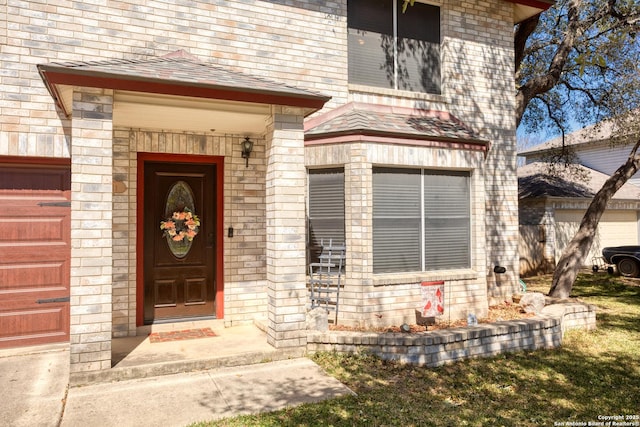 doorway to property with an attached garage and brick siding