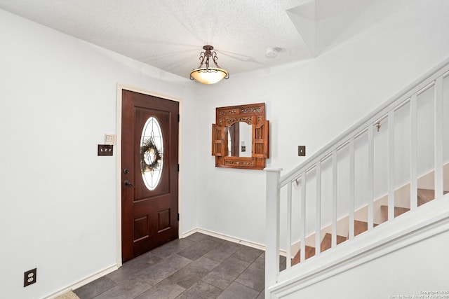 entrance foyer with a textured ceiling and stairs