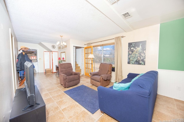 living room with visible vents, a chandelier, a textured ceiling, and wainscoting