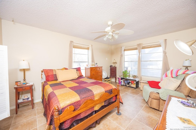 bedroom with a ceiling fan, light tile patterned flooring, and a textured ceiling