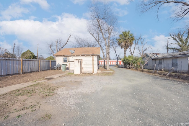 exterior space featuring driveway, a shed, and fence