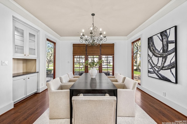 dining area with dark wood-style floors, crown molding, and a notable chandelier