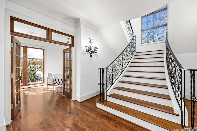 staircase featuring a notable chandelier, baseboards, and wood finished floors