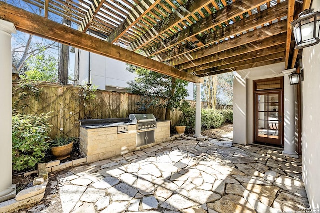 view of patio / terrace with exterior kitchen, a grill, fence, and a pergola