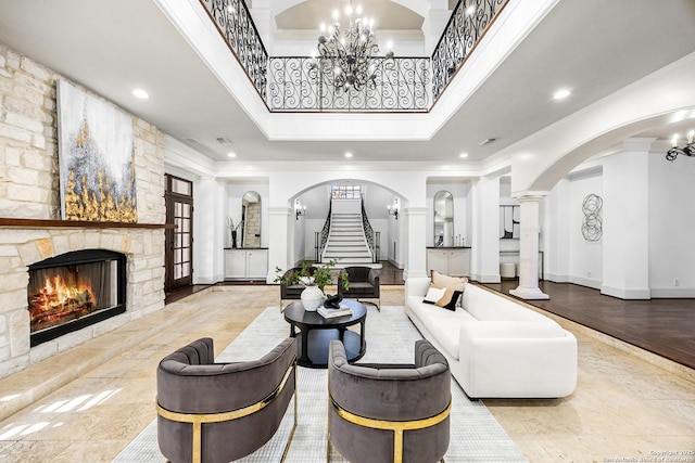 living room featuring arched walkways, a fireplace, a chandelier, and crown molding