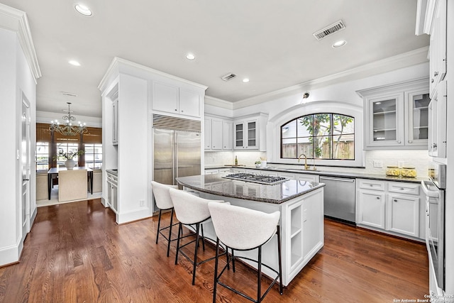 kitchen featuring a notable chandelier, a sink, visible vents, appliances with stainless steel finishes, and a center island