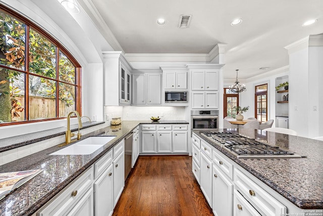 kitchen with visible vents, decorative backsplash, ornamental molding, stainless steel appliances, and a sink