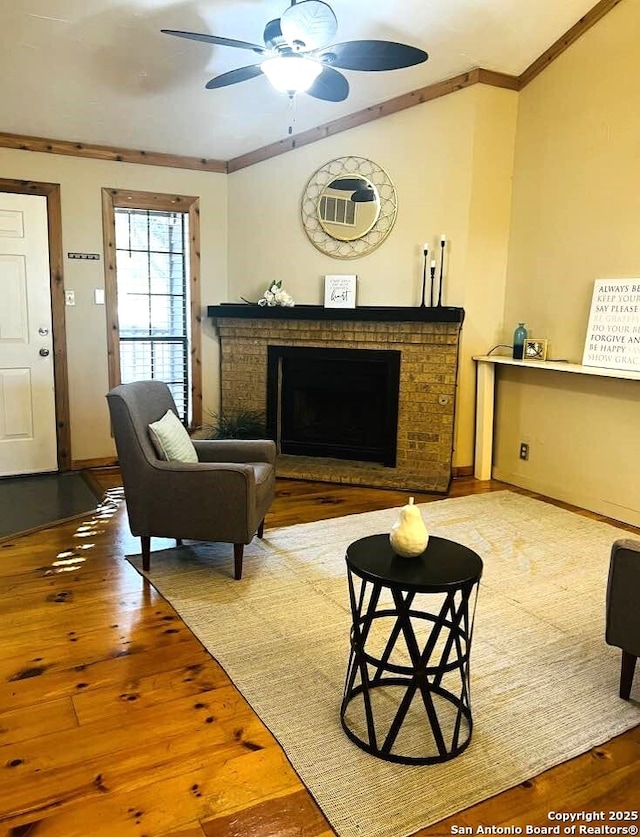 living room with crown molding, a fireplace, ceiling fan, baseboards, and hardwood / wood-style flooring