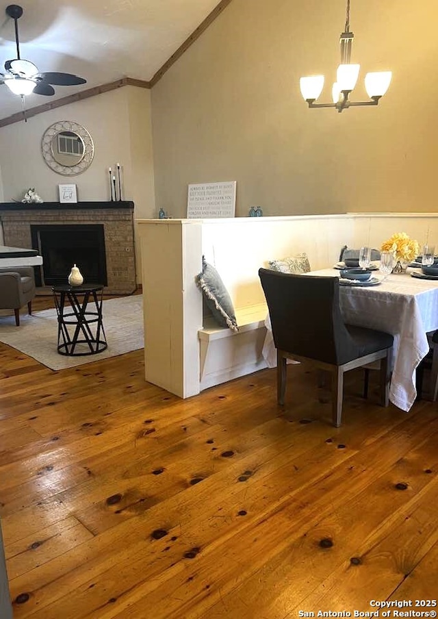 dining space featuring ornamental molding, lofted ceiling, wood-type flooring, and ceiling fan with notable chandelier