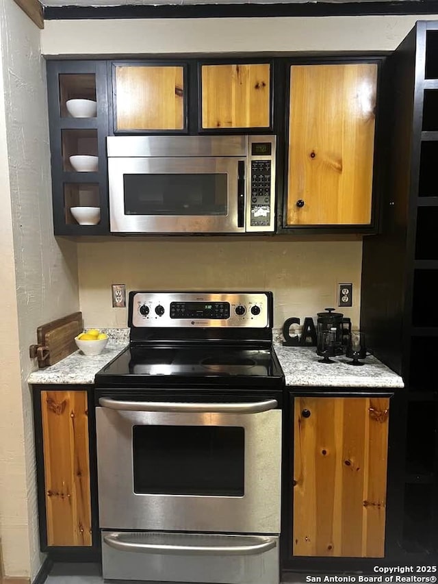 kitchen featuring stainless steel appliances, light countertops, and brown cabinets