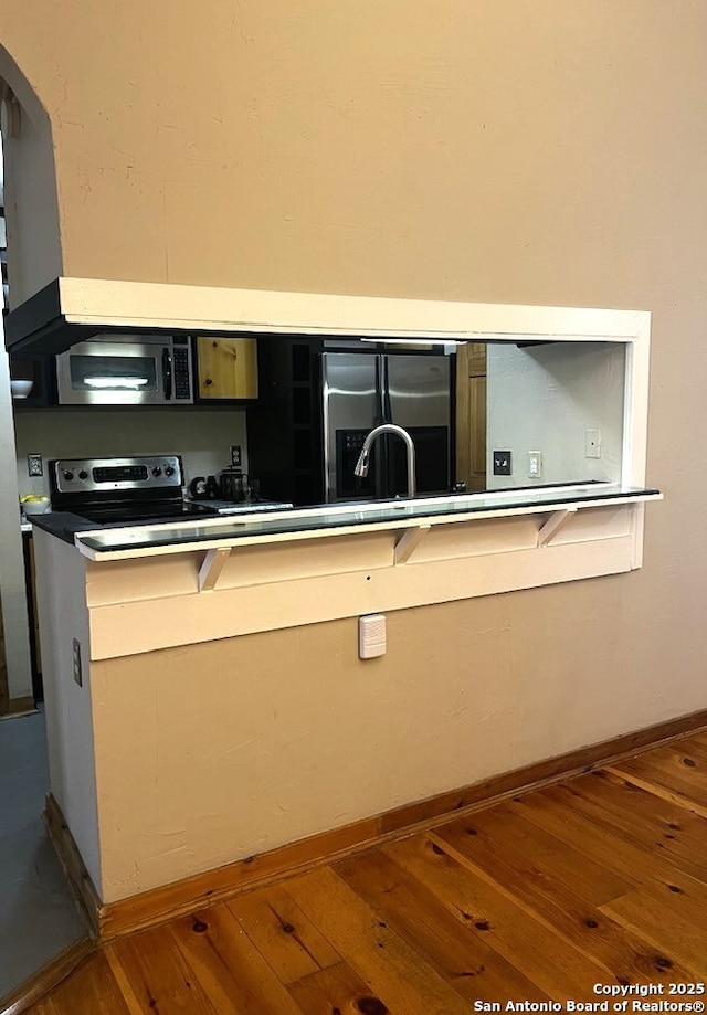 kitchen featuring appliances with stainless steel finishes, baseboards, and hardwood / wood-style flooring