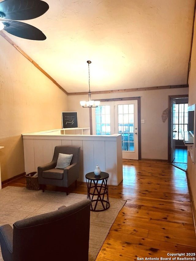 living area with wood-type flooring, a chandelier, vaulted ceiling, and crown molding