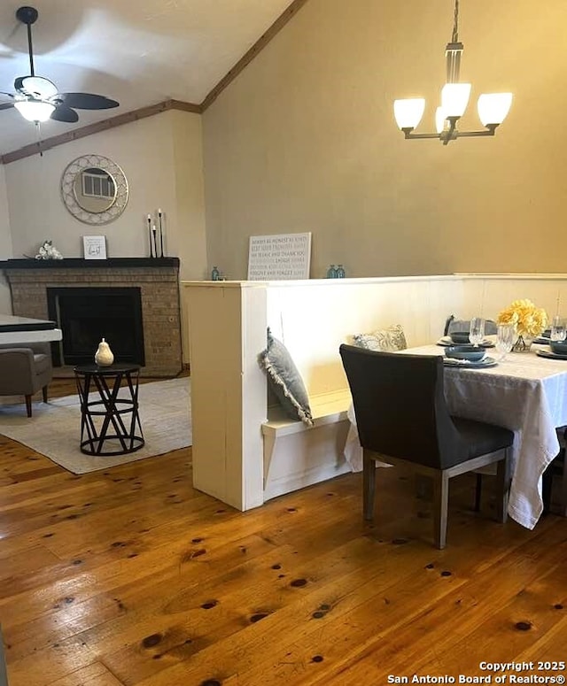 dining space featuring lofted ceiling, ceiling fan with notable chandelier, hardwood / wood-style flooring, and crown molding