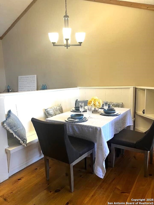 dining space with lofted ceiling, an inviting chandelier, and wood finished floors