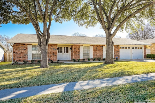 ranch-style home with an attached garage, a front lawn, concrete driveway, and brick siding