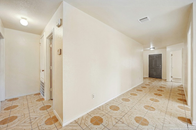 hallway featuring light tile patterned floors, visible vents, and baseboards