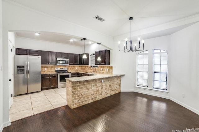 kitchen with dark brown cabinetry, a peninsula, visible vents, appliances with stainless steel finishes, and decorative backsplash