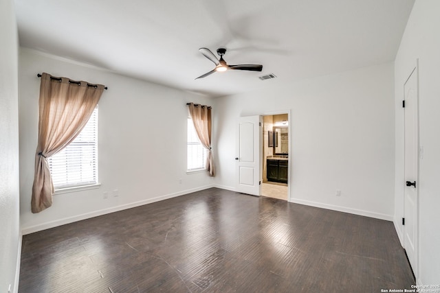 unfurnished bedroom featuring dark wood-style floors, ensuite bath, visible vents, and baseboards