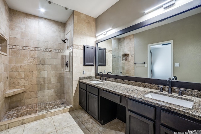 bathroom featuring a tile shower, double vanity, and a sink