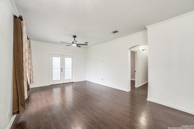 empty room with arched walkways, visible vents, ornamental molding, french doors, and dark wood finished floors