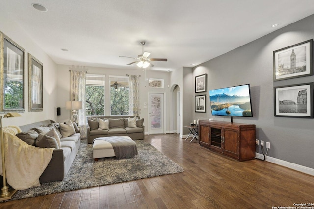 living room featuring a ceiling fan, arched walkways, baseboards, and hardwood / wood-style flooring