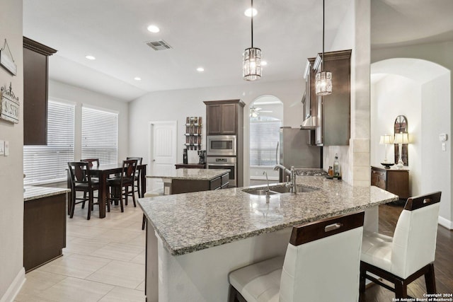 kitchen featuring arched walkways, stainless steel appliances, a peninsula, a sink, and visible vents